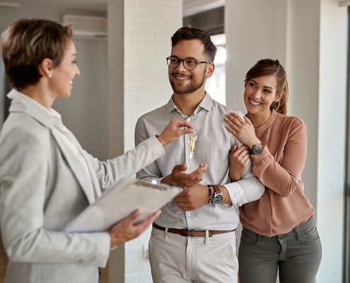 Junges Paar erhält Schlüssel von Immobilienmaklerin